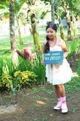 The junior maid of honor carrying HERE COMES THE BRIDE SIGN
